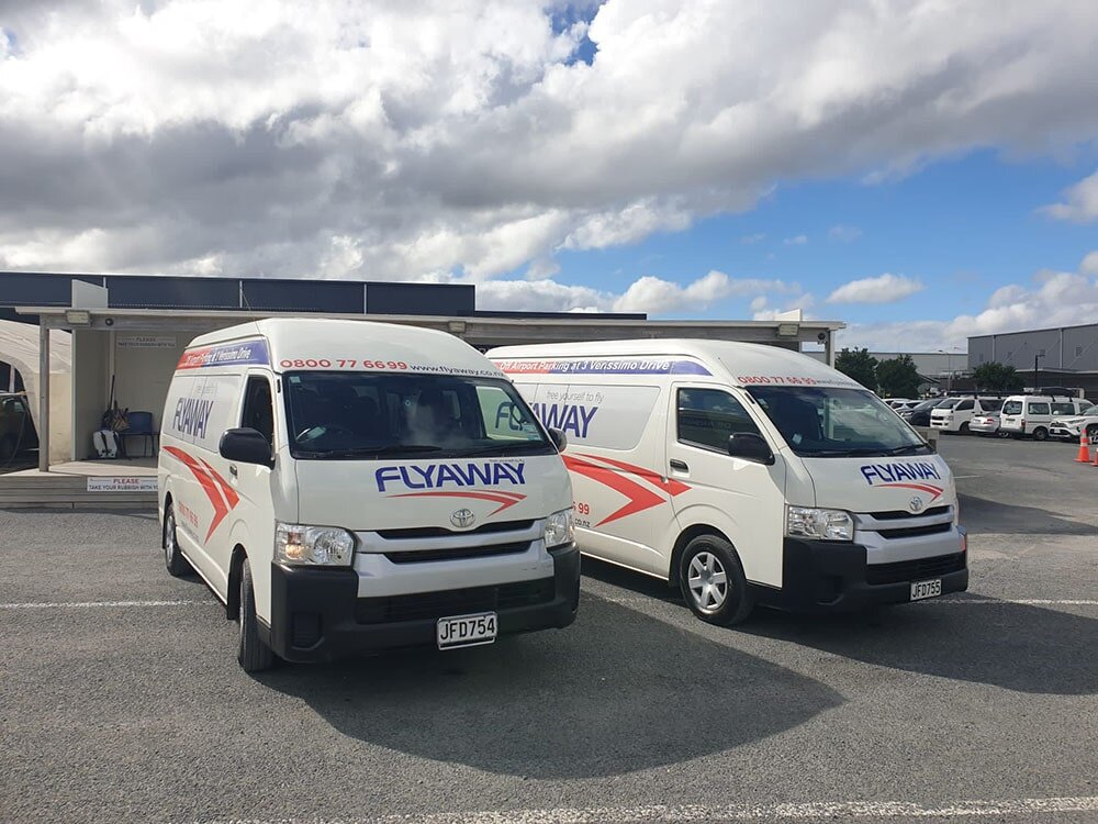 flyaway shuttle buses Two white Flyaway shuttle vans parked side by side at the secure Auckland off-site parking facility